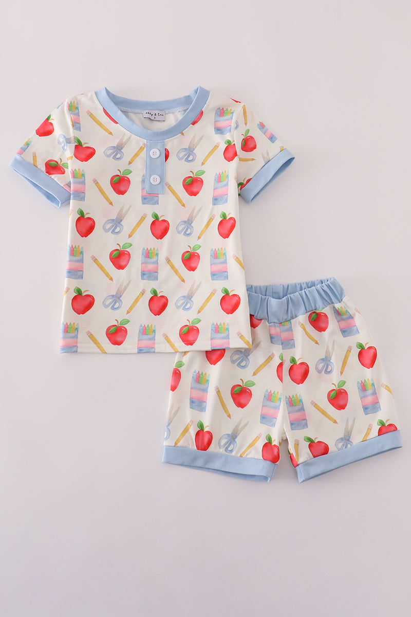 Children's pajama set with apple and school supplies pattern on a light gray background