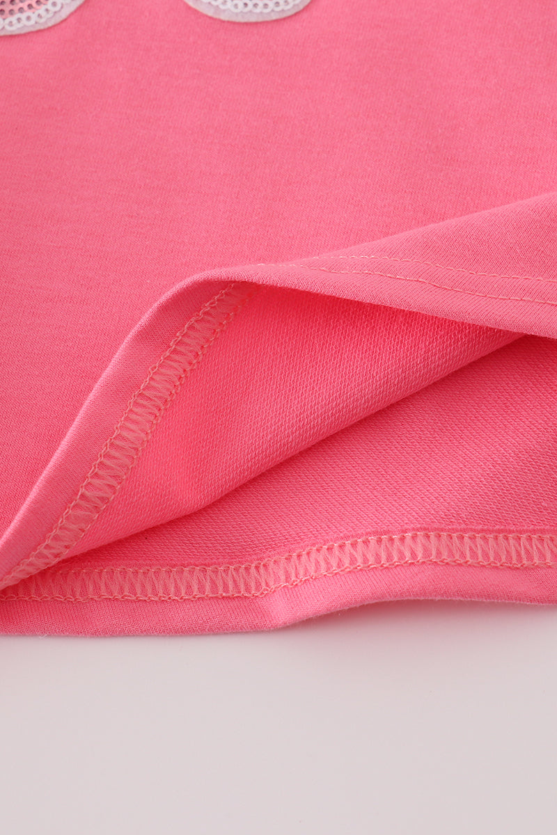 Close-up of pink fabric with visible stitching on a light gray background