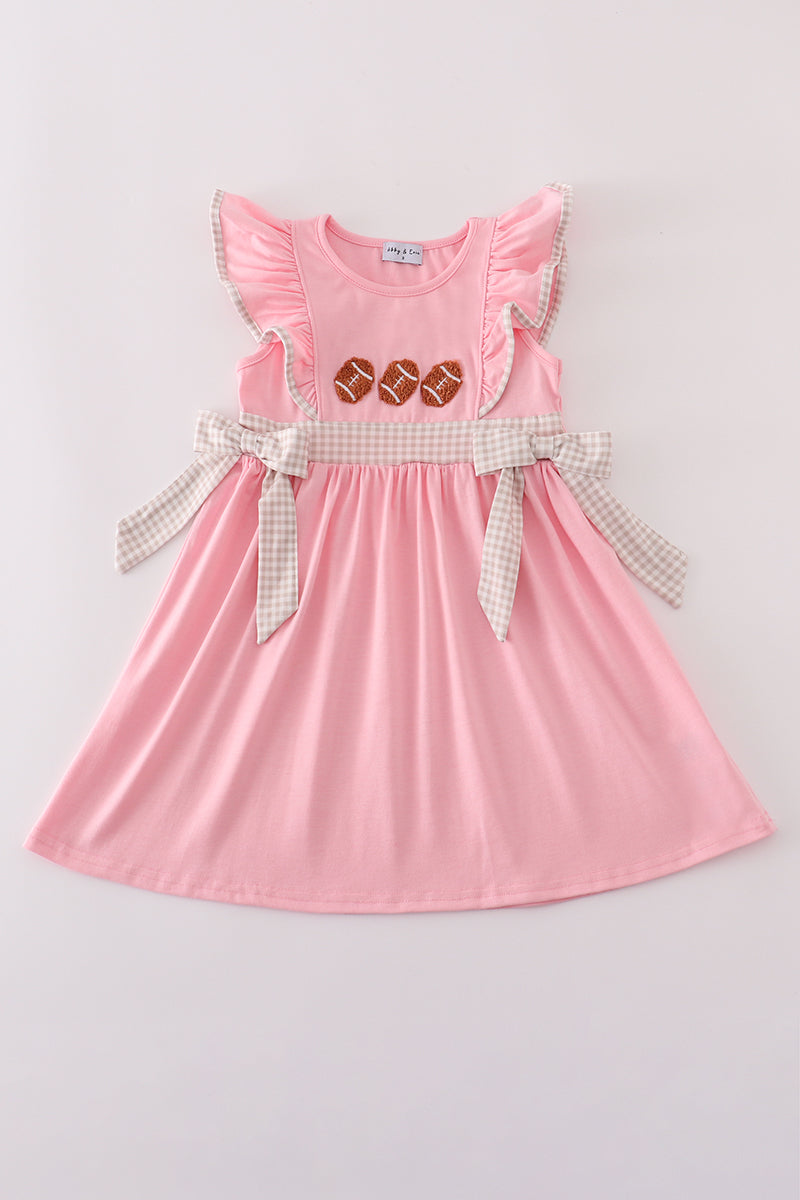 Pink dress with ruffled sleeves and a checkered belt on a light gray background
