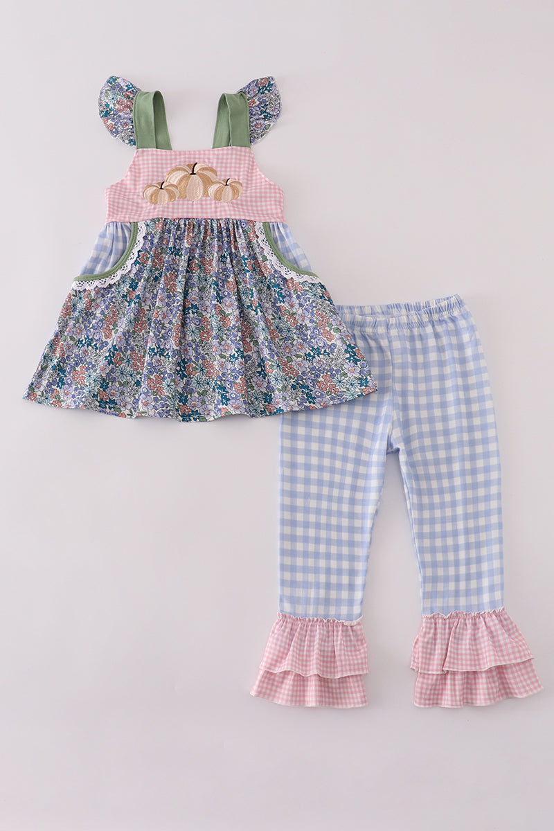 Children's outfit with floral top and gingham pants on a light gray background