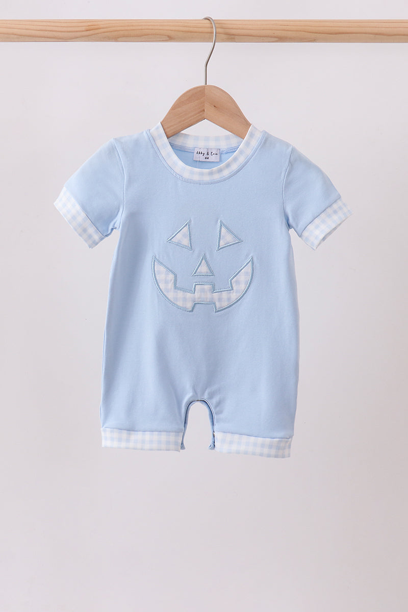 A baby short-sleeve romper in light blue, hanging on a wooden hanger. The romper features a light blue and white gingham pattern on the collar, sleeve cuffs, and hem, with a light blue embroidered jack-o'-lantern face on the front.