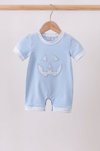 A baby short-sleeve romper in light blue, hanging on a wooden hanger. The romper features a light blue and white gingham pattern on the collar, sleeve cuffs, and hem, with a light blue embroidered jack-o'-lantern face on the front.