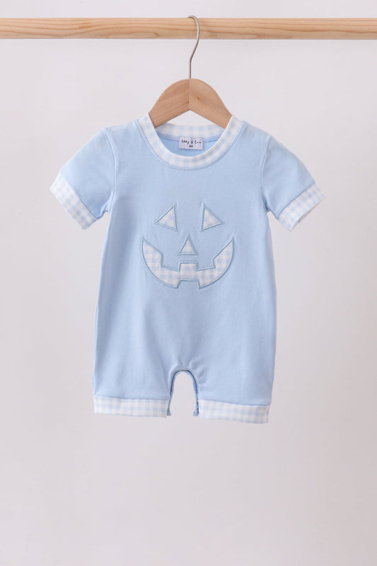 A baby short-sleeve romper in light blue, hanging on a wooden hanger. The romper features a light blue and white gingham pattern on the collar, sleeve cuffs, and hem, with a light blue embroidered jack-o'-lantern face on the front.
