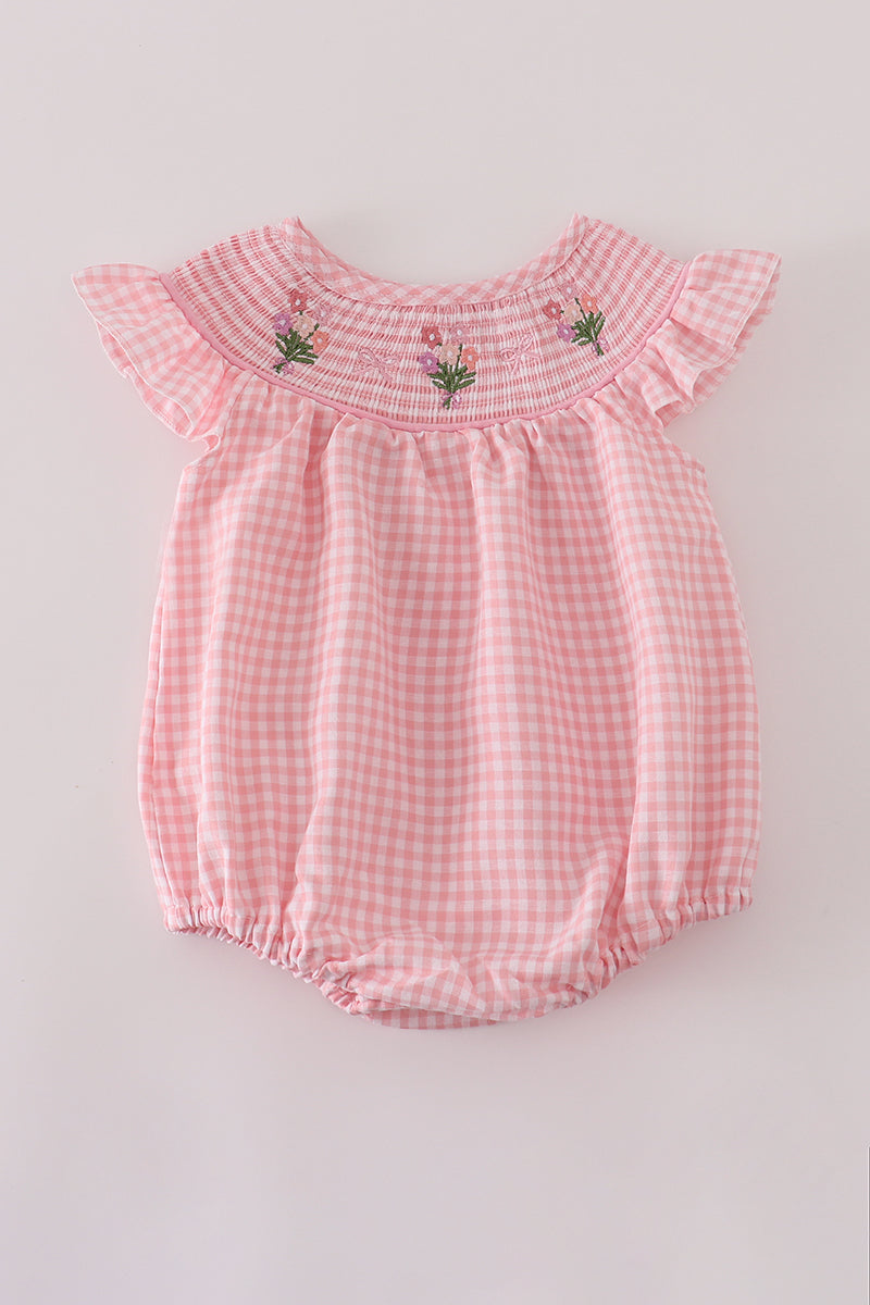 Pink checkered baby romper with floral embroidery on a light gray background