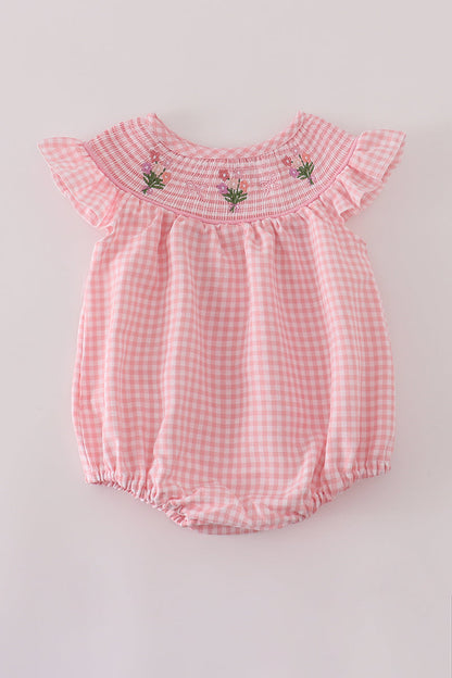 Pink checkered baby romper with floral embroidery on a light gray background