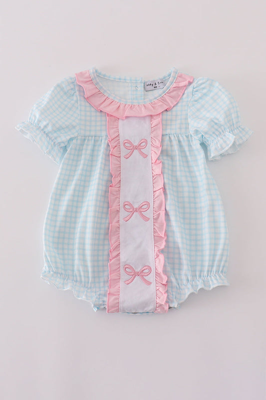 Baby romper with checkered pattern and pink ribbons on a light gray background