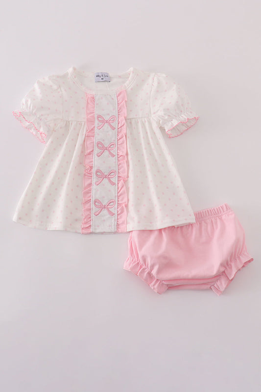White dress with pink embroidery and matching bloomers on a light gray background