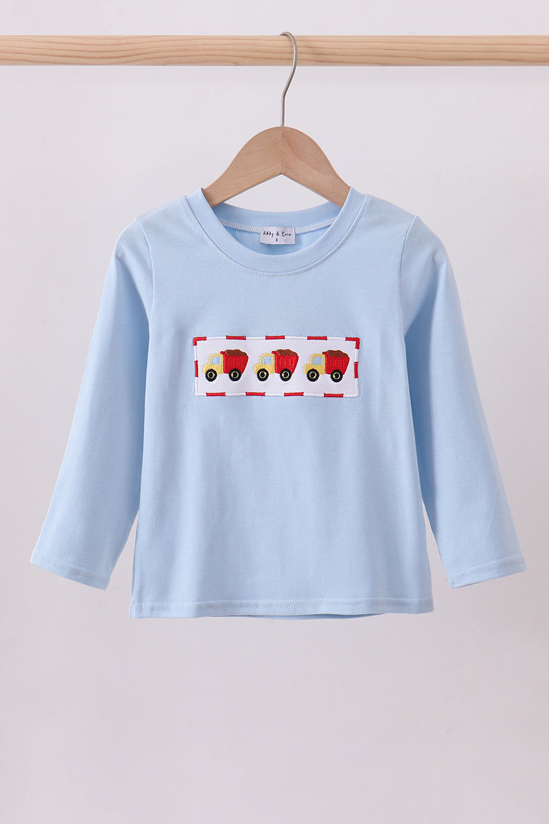 Light blue long-sleeve shirt with a colorful graphic on a wooden hanger against a light background