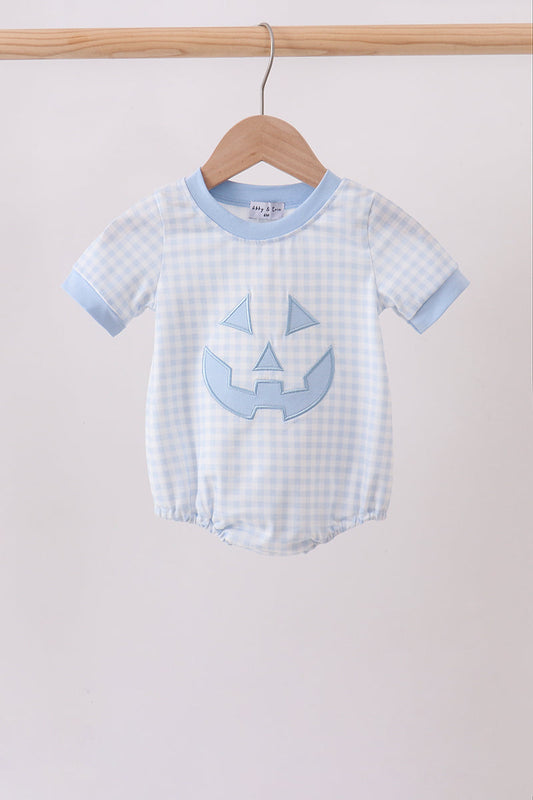 A baby short-sleeve romper in a light blue and white gingham pattern, featuring a light blue pumpkin face applique on the front and light blue ribbed trim, hanging on a wooden hanger.