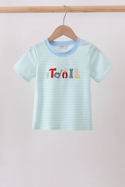 A light blue and white striped short-sleeve baby t-shirt hanging on a wooden hanger. The shirt features a light blue crew neck and a colorful graphic on the chest spelling 'TOY' using different colored letters.