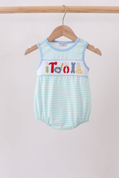 A baby romper with light blue and white stripes, featuring a white chest panel with colorful letters spelling 'Troll' and small multicolor icons. The romper is displayed on a wooden hanger hanging from a wooden clothes rack against a plain light gray background.