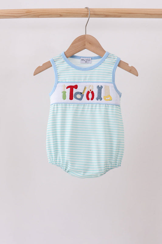 A baby romper with light blue and white stripes, featuring a white chest panel with colorful letters spelling 'Troll' and small multicolor icons. The romper is displayed on a wooden hanger hanging from a wooden clothes rack against a plain light gray background.