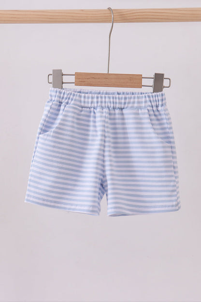 Striped shorts hanging on a wooden hanger against a light background