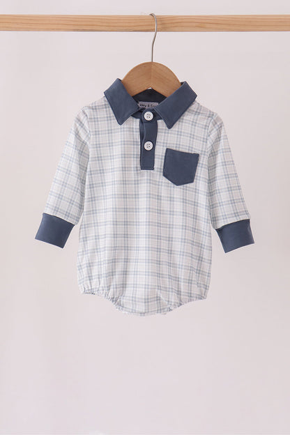 A baby long-sleeve polo romper with a light blue and white plaid pattern, featuring solid navy blue collar, cuffs, and chest pocket, hanging on a wooden hanger.