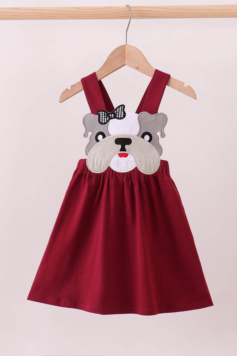 Red dress with bulldog face design on a hanger against a white background