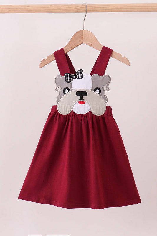 Red dress with bulldog face design on a hanger against a white background