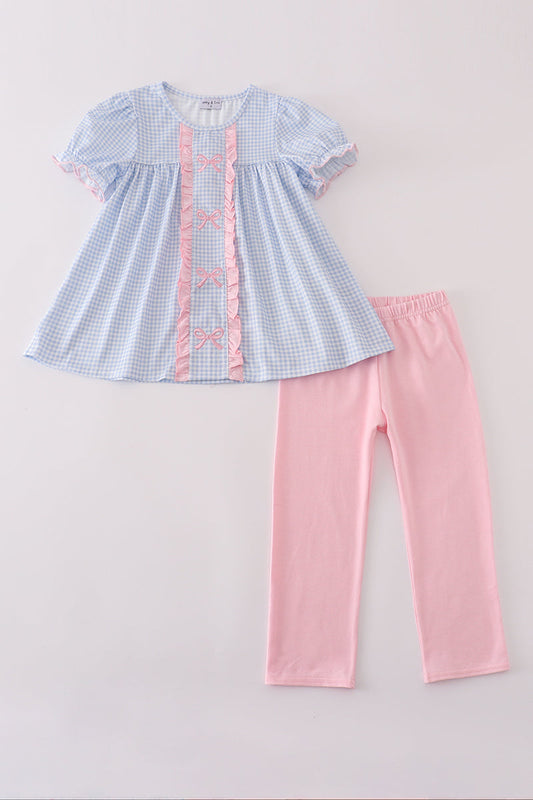 Children's outfit with blue checkered top and pink pants on a light gray background
