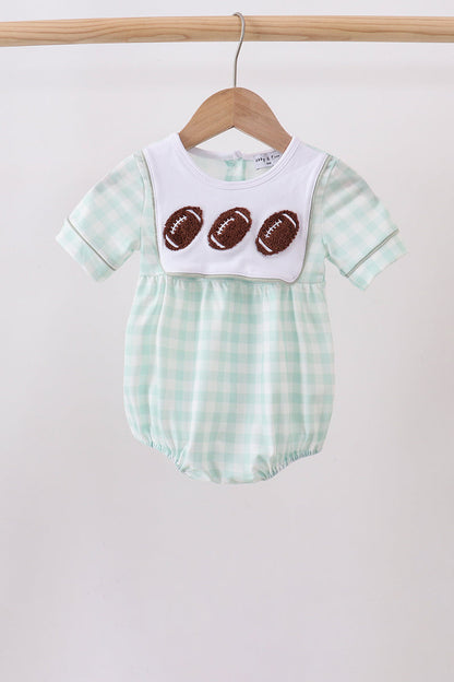 A baby short-sleeve romper in a mint green and white gingham pattern, featuring a white bib-style chest panel with three brown football appliqués, hanging on a wooden hanger.