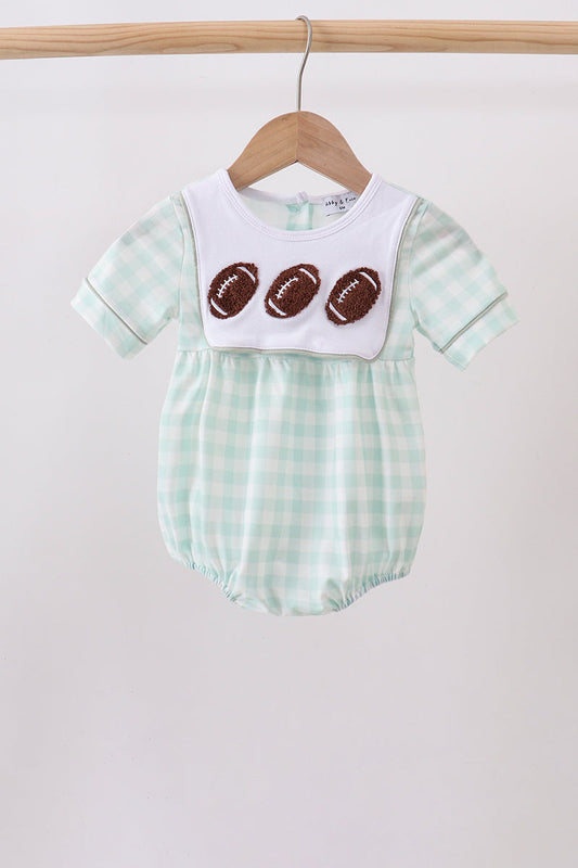 A baby short-sleeve romper in a mint green and white gingham pattern, featuring a white bib-style chest panel with three brown football appliqués, hanging on a wooden hanger.
