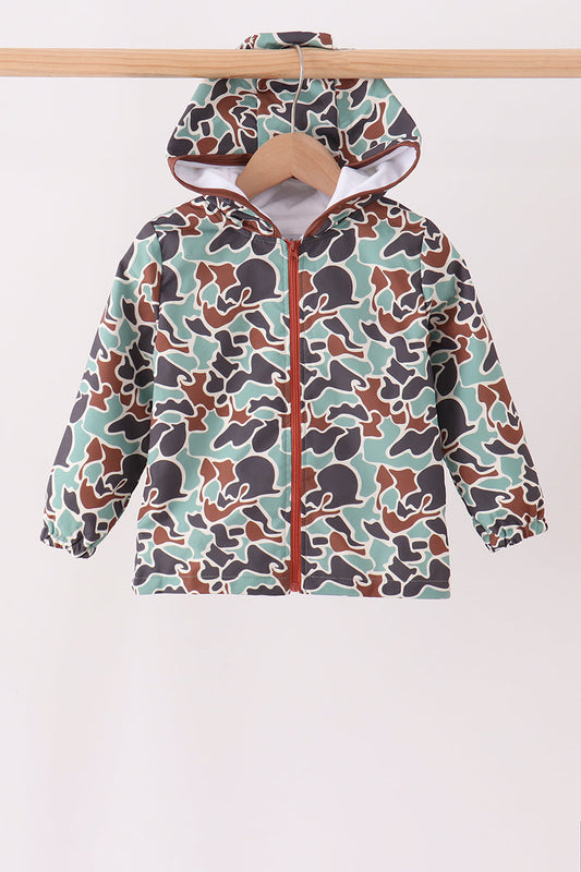 A hooded zip-up jacket with a camouflage pattern in sage green, brown, and dark gray, hanging on a wooden hanger against a plain light background.