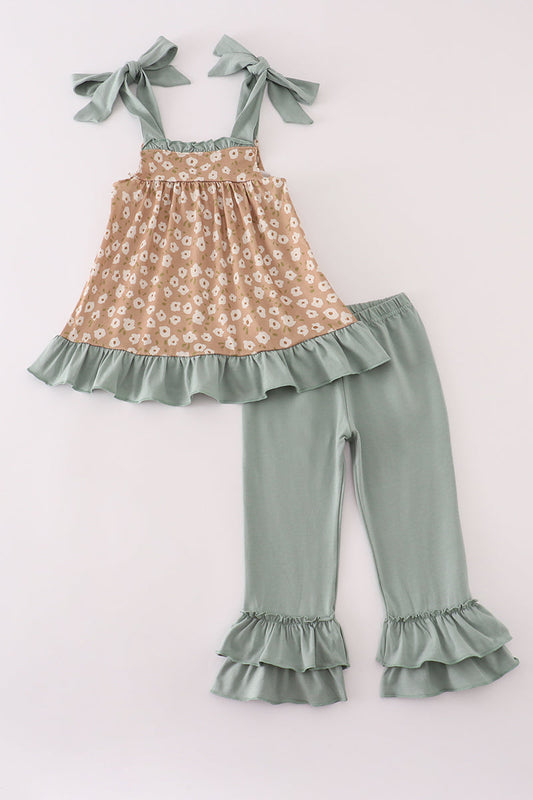 Children's outfit with floral top and ruffled pants on a light pink background