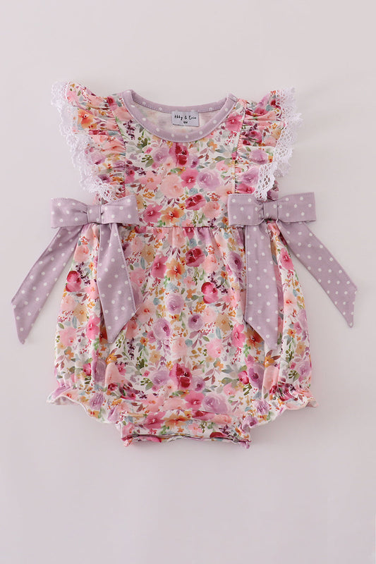 Floral baby romper with ruffles and bows on a white background