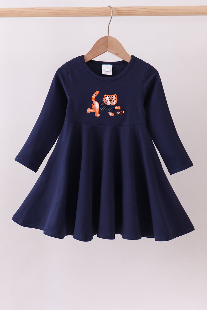 Navy blue dress with a tiger design on a hanger against a white background