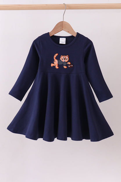 Navy blue dress with a tiger design on a hanger against a white background