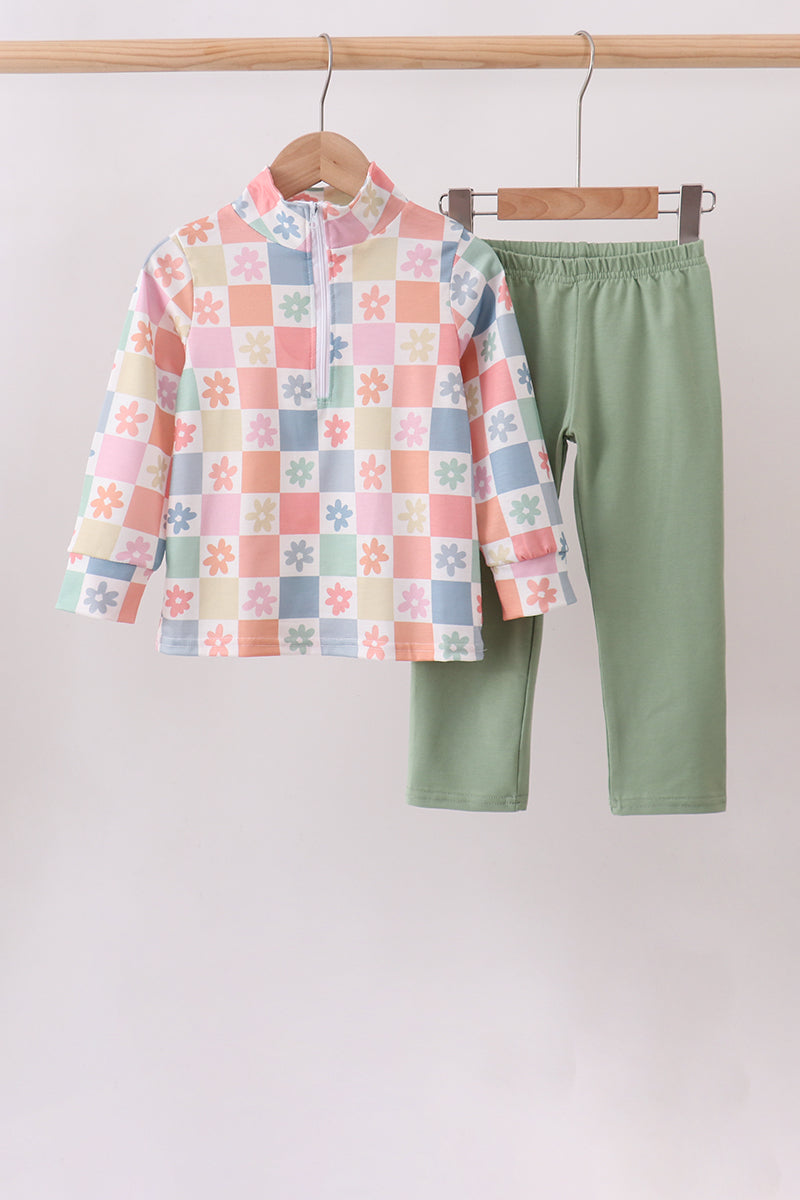 A children's two-piece clothing set hanging on wooden hangers against a plain light background. The set includes a long-sleeve mock-neck top with a pastel multicolor checkered pattern featuring small floral motifs, and solid sage green pants.