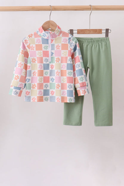 A children's two-piece clothing set hanging on wooden hangers against a plain light background. The set includes a long-sleeve mock-neck top with a pastel multicolor checkered pattern featuring small floral motifs, and solid sage green pants.
