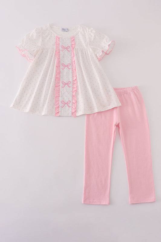 White top with pink trim and pink pants on a light gray background