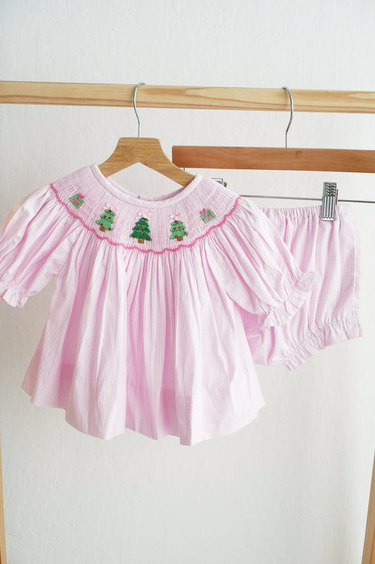 Pink baby outfit with embroidered details on a hanger against a white background