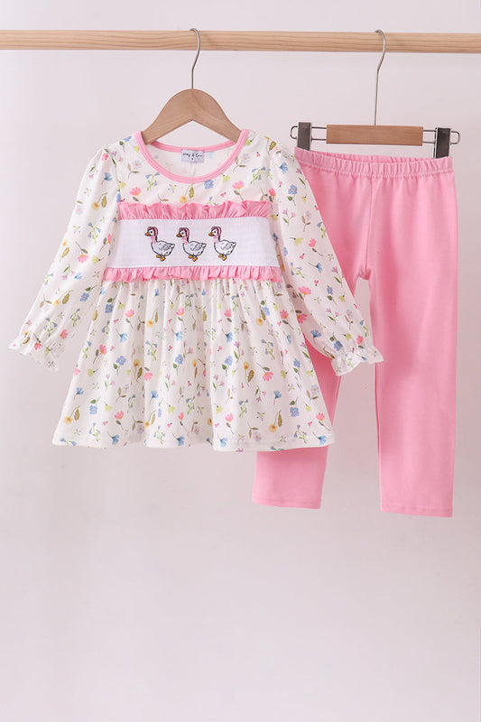 Children's dress and pink pants on hangers against a light background