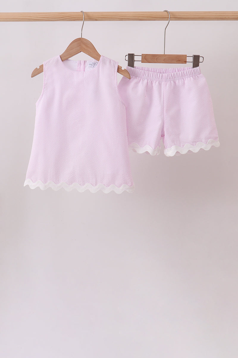 Light pink shorts with lace trim on a wooden hanger against a plain background