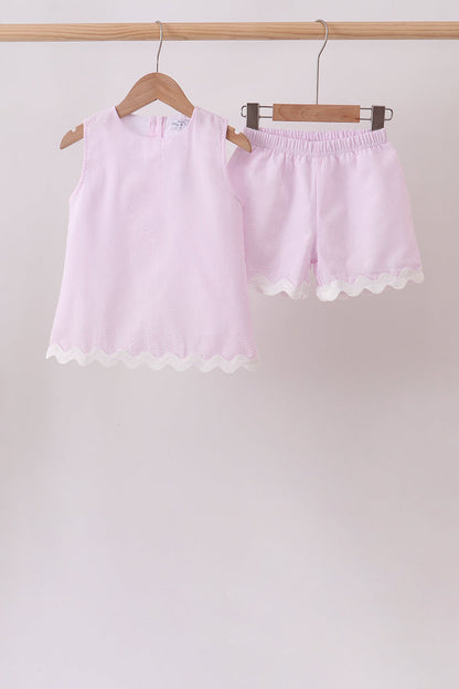 Light pink shorts with lace trim on a wooden hanger against a plain background