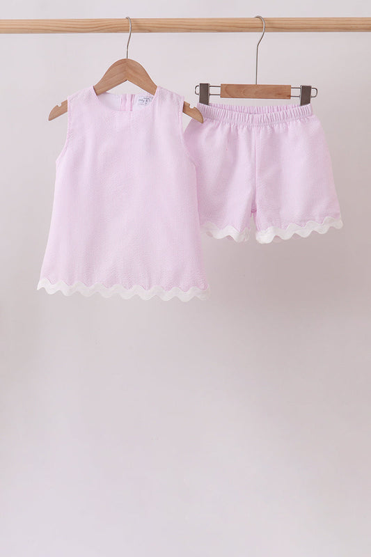 Light pink shorts with lace trim on a wooden hanger against a plain background