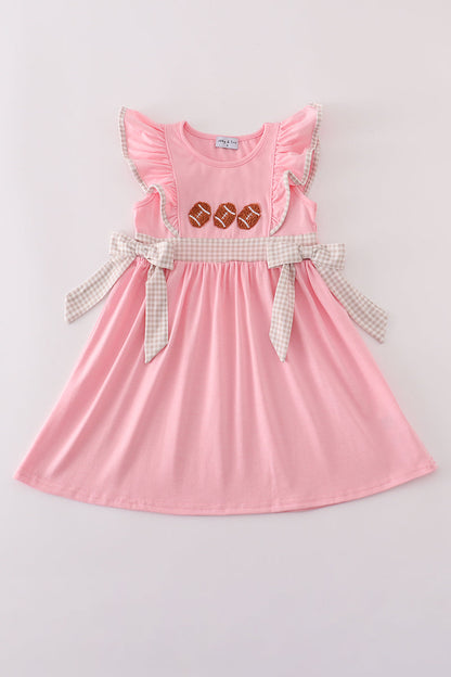 Pink dress with ruffled sleeves and a checkered belt on a light gray background