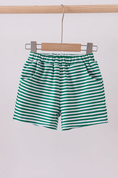 Green and white striped shorts hanging on a wooden hanger against a white background