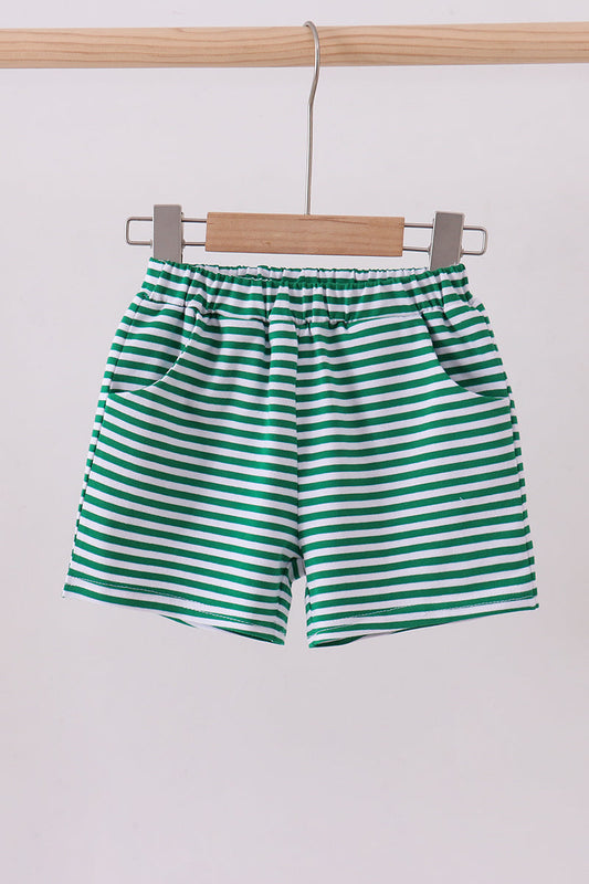 Green and white striped shorts hanging on a wooden hanger against a white background