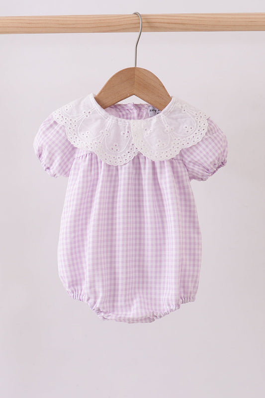 Purple checkered baby romper with white collar on a wooden hanger against a light gray background
