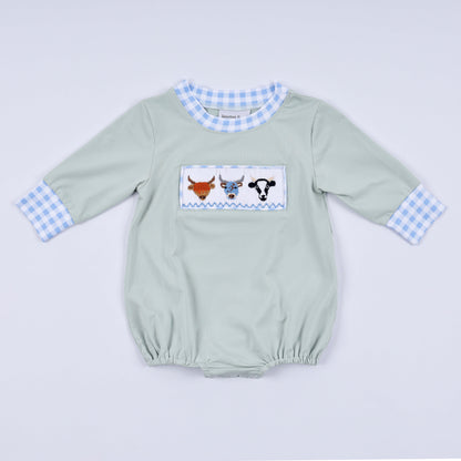 Light green baby romper with checkered sleeves and cow design on a light gray background