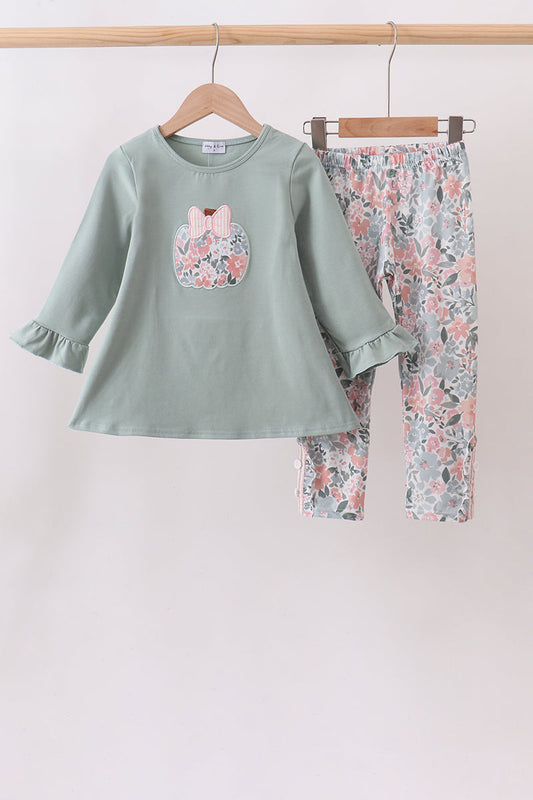A children's two-piece clothing set hanging on wooden hangers against a plain light background. The set includes a sage green long-sleeve top with a floral bunny patch on the chest and matching floral print pants.