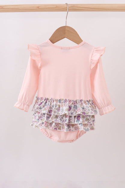 Pink top and floral bloomers on a wooden hanger against a light gray background