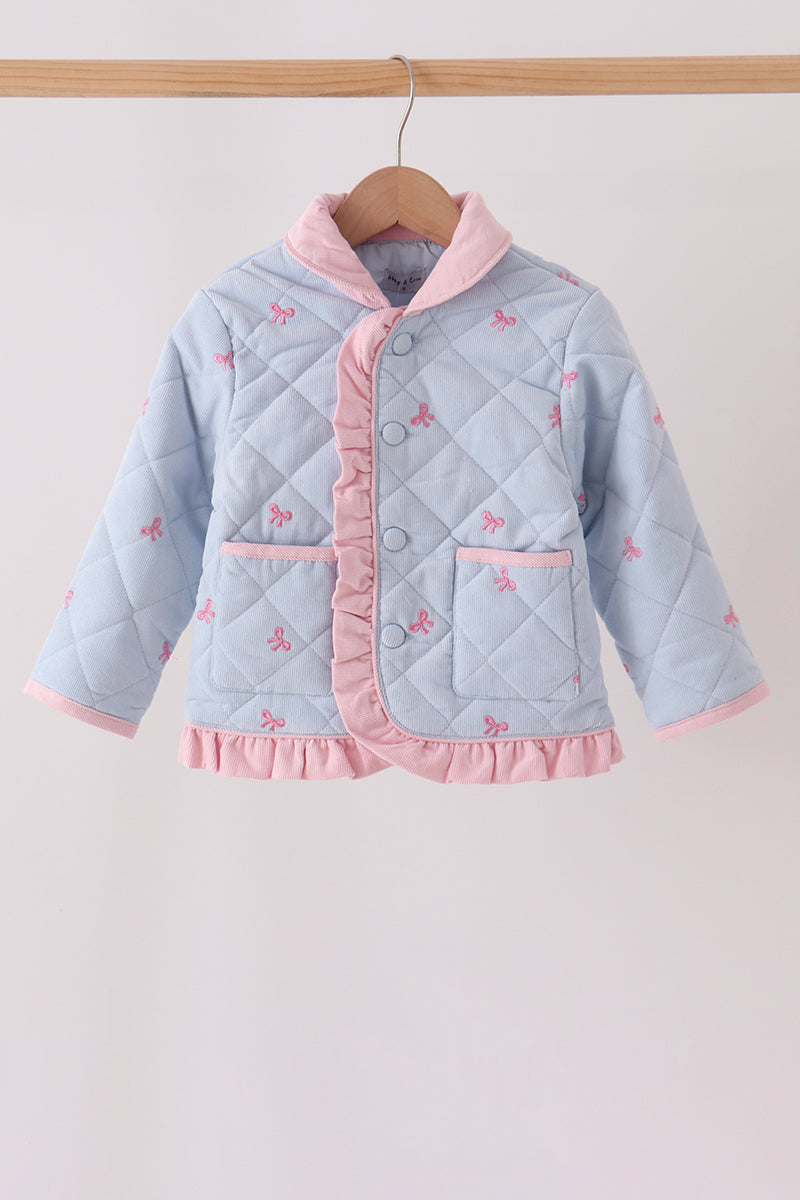 A light blue quilted baby jacket with pink ruffle trim and small pink bow details, hanging on a wooden hanger against a plain light background.